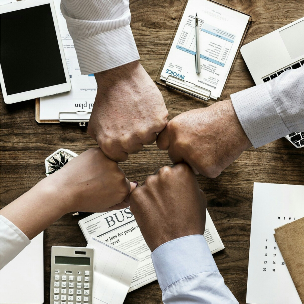 Une formation professionnelle de gens d'affaires réunis autour d'un bureau, unis dans un poing.