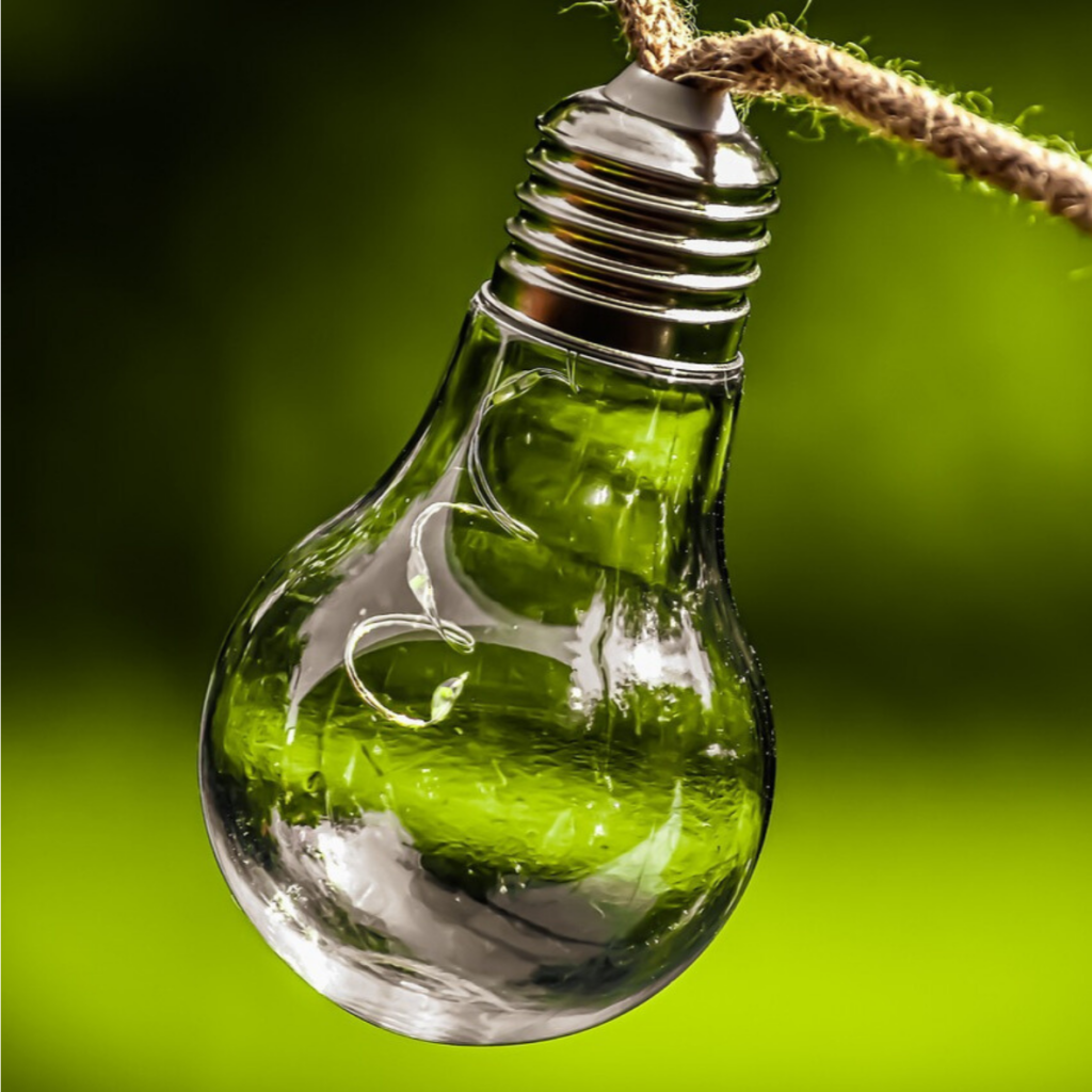 A light bulb hanging from a rope with a green background.